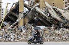 Homem anda de motociclo diante de destroços de prédios em Gaza
