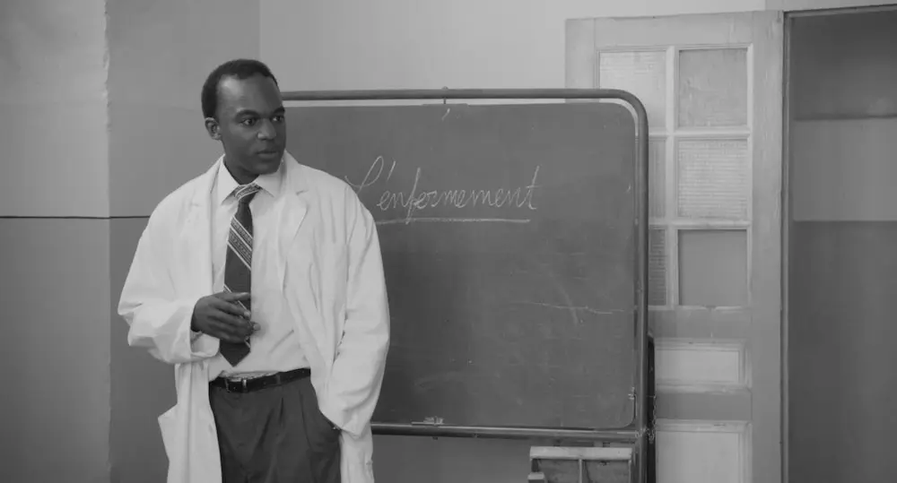 Fanon com jaleco de médico, provavelmente em aula