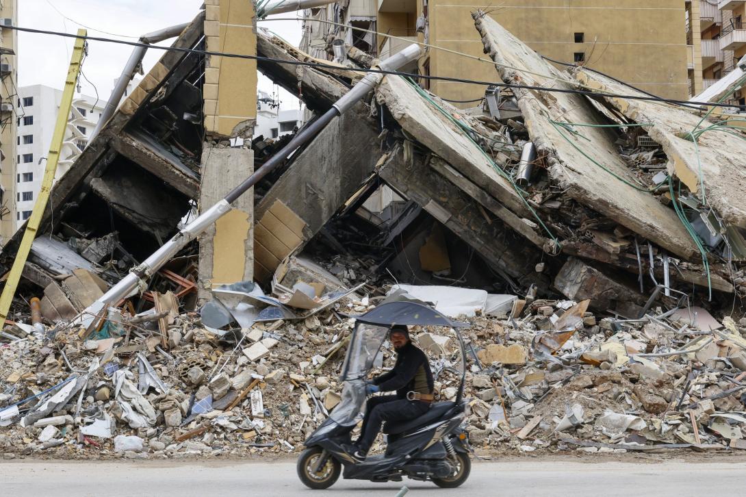 Homem anda de motociclo diante de destroços de prédios em Gaza